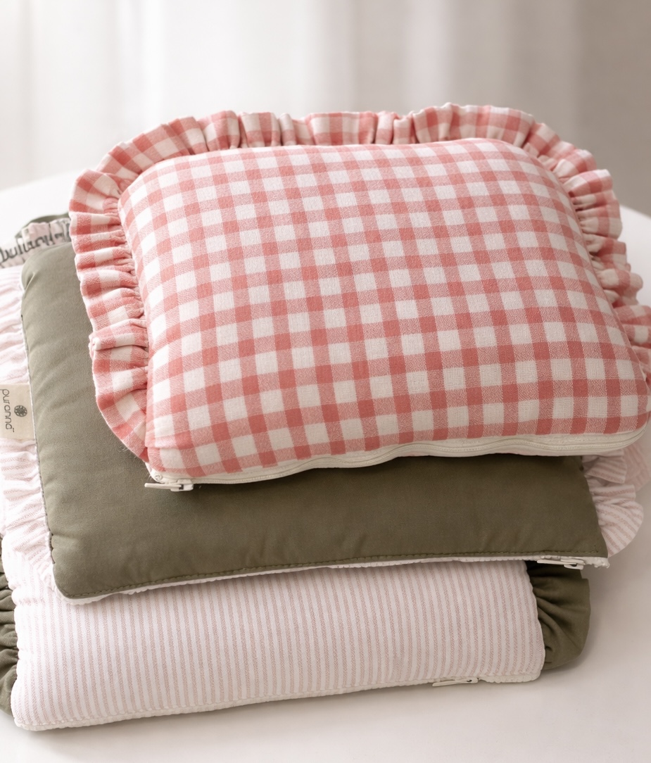 Três almofadas empilhadas em tons rosa, branco e verde-oliva com diferentes padrões e babados.