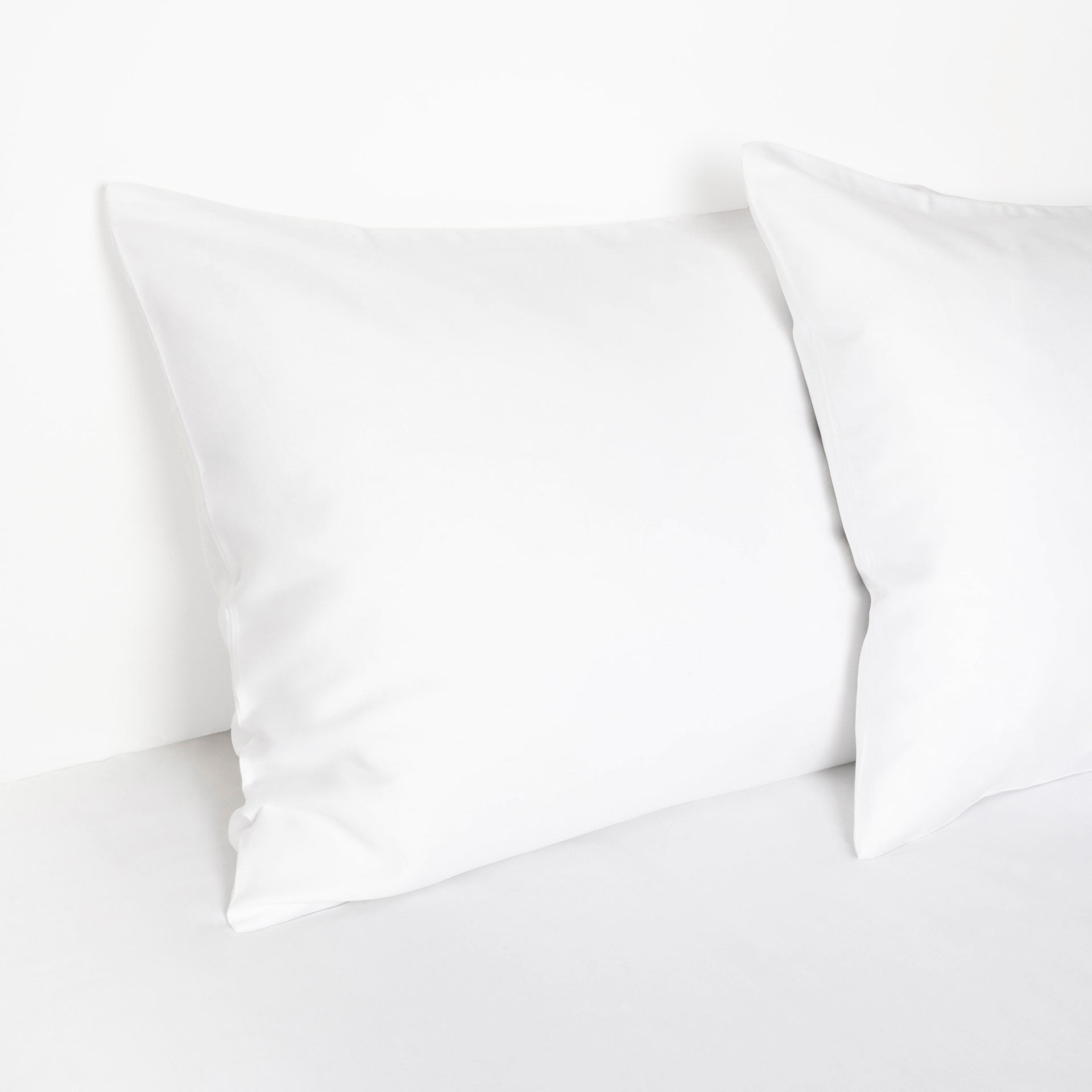 Travesseiros brancos quadrados sobre superfície branca