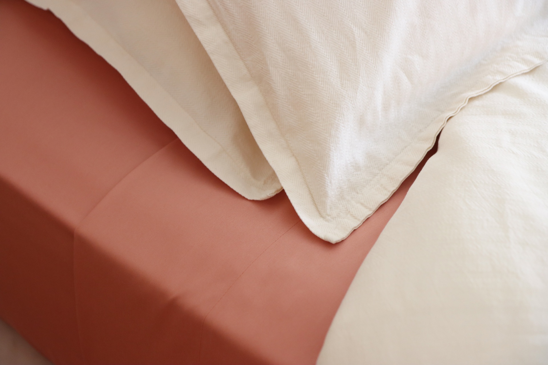 lençol terracota com fronhas e cobertores brancos