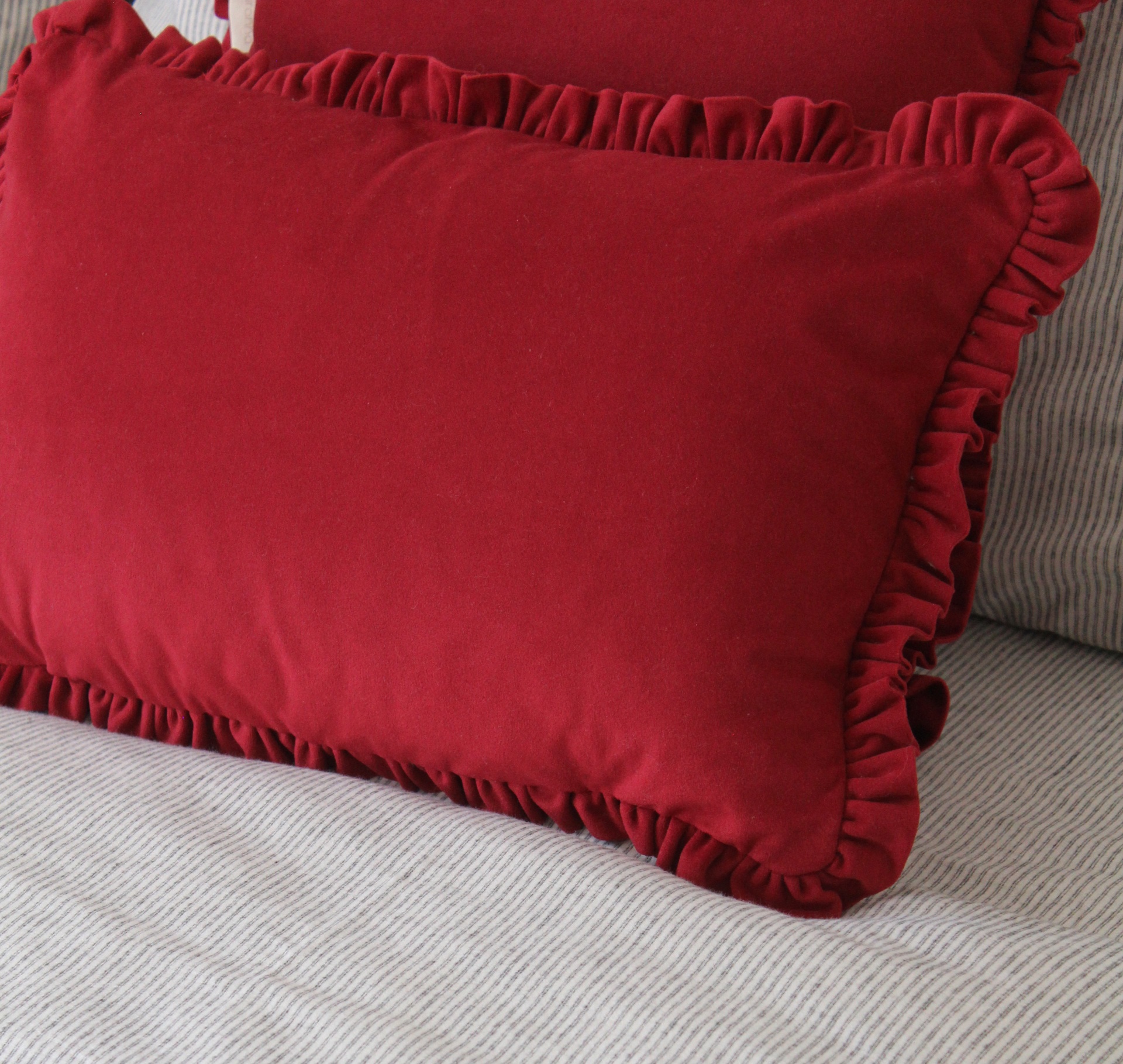 Almofada vermelha com folhos em cima de superfície cinzenta riscada