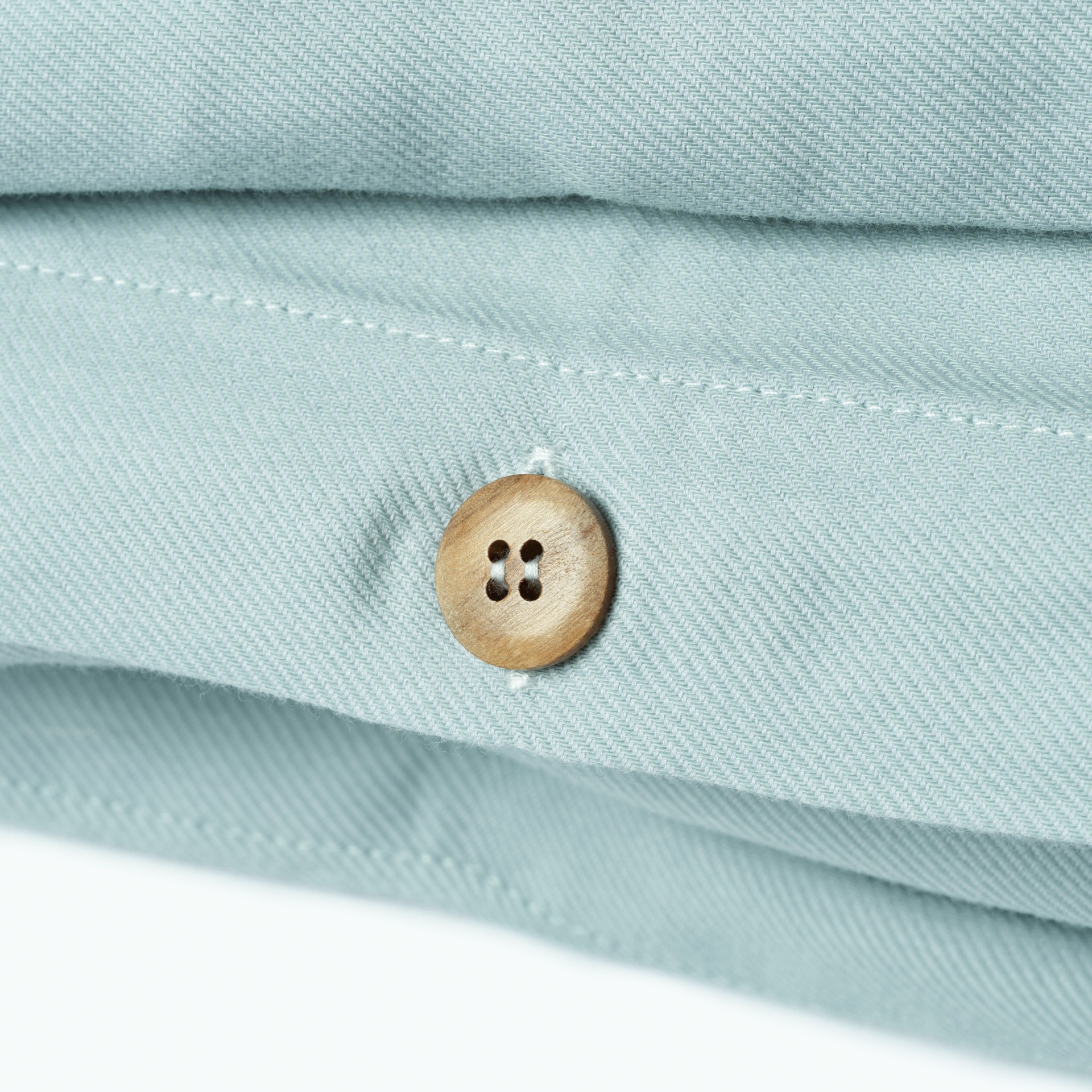 Botão de madeira numa camisa azul clara com tecido texturizado