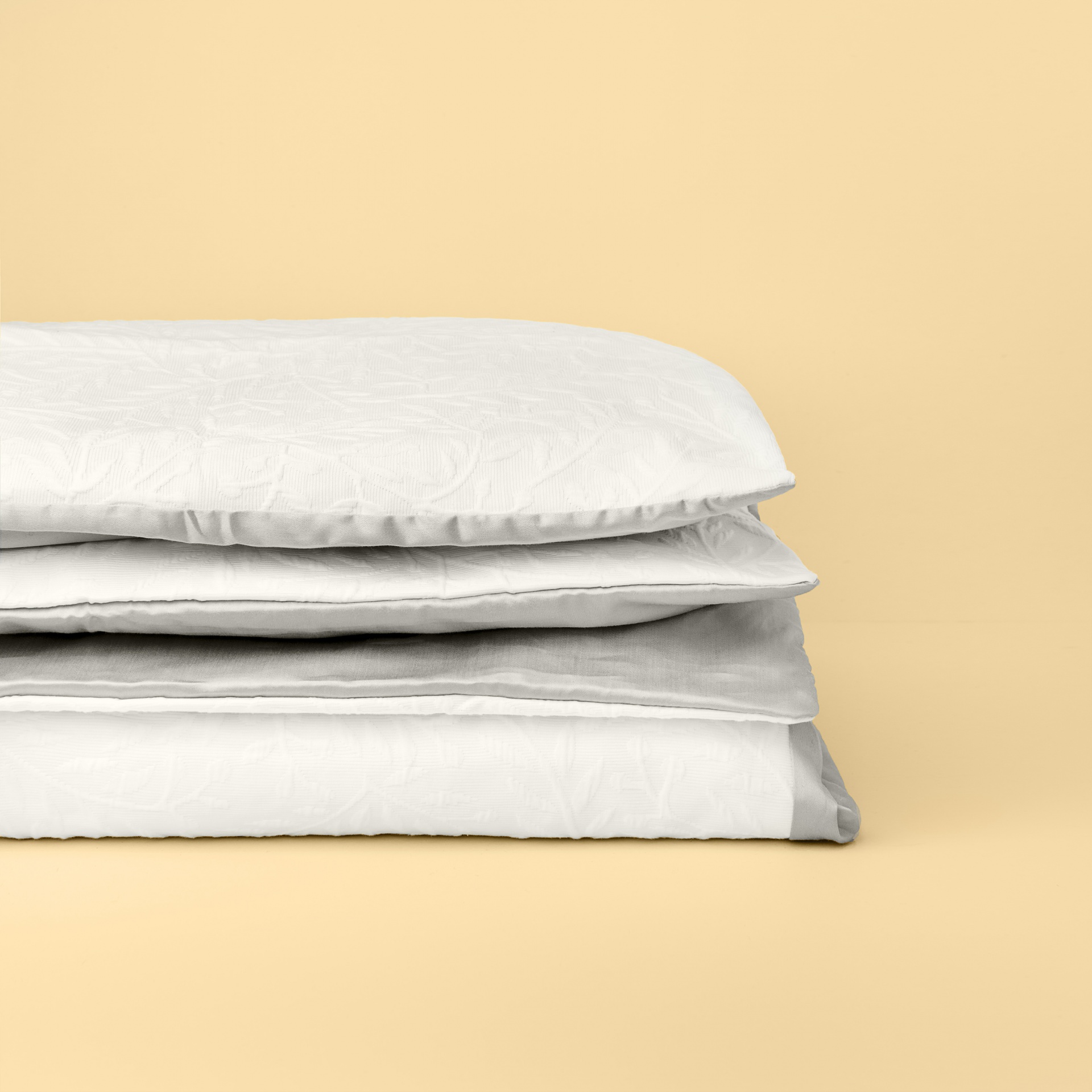 Colcha branca lisa empilhada sobre fundo bege