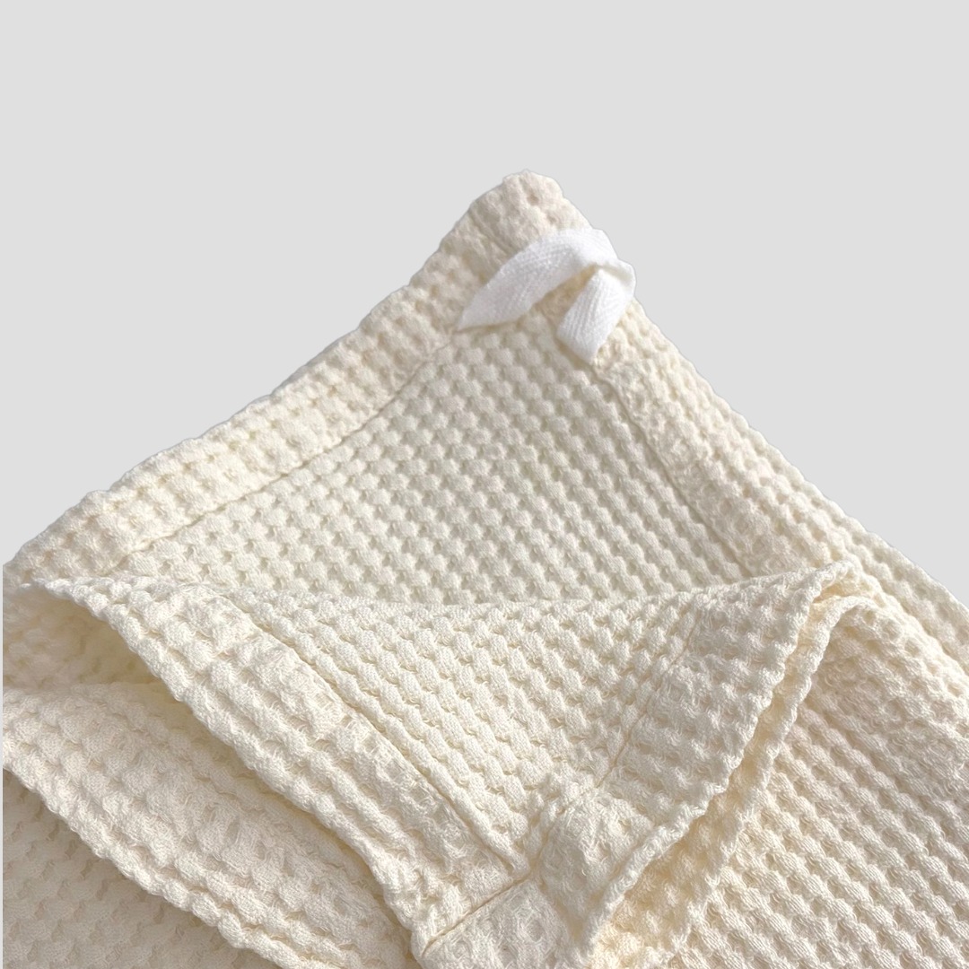 Toalha branca texturizada dobrada sobre fundo cinzento