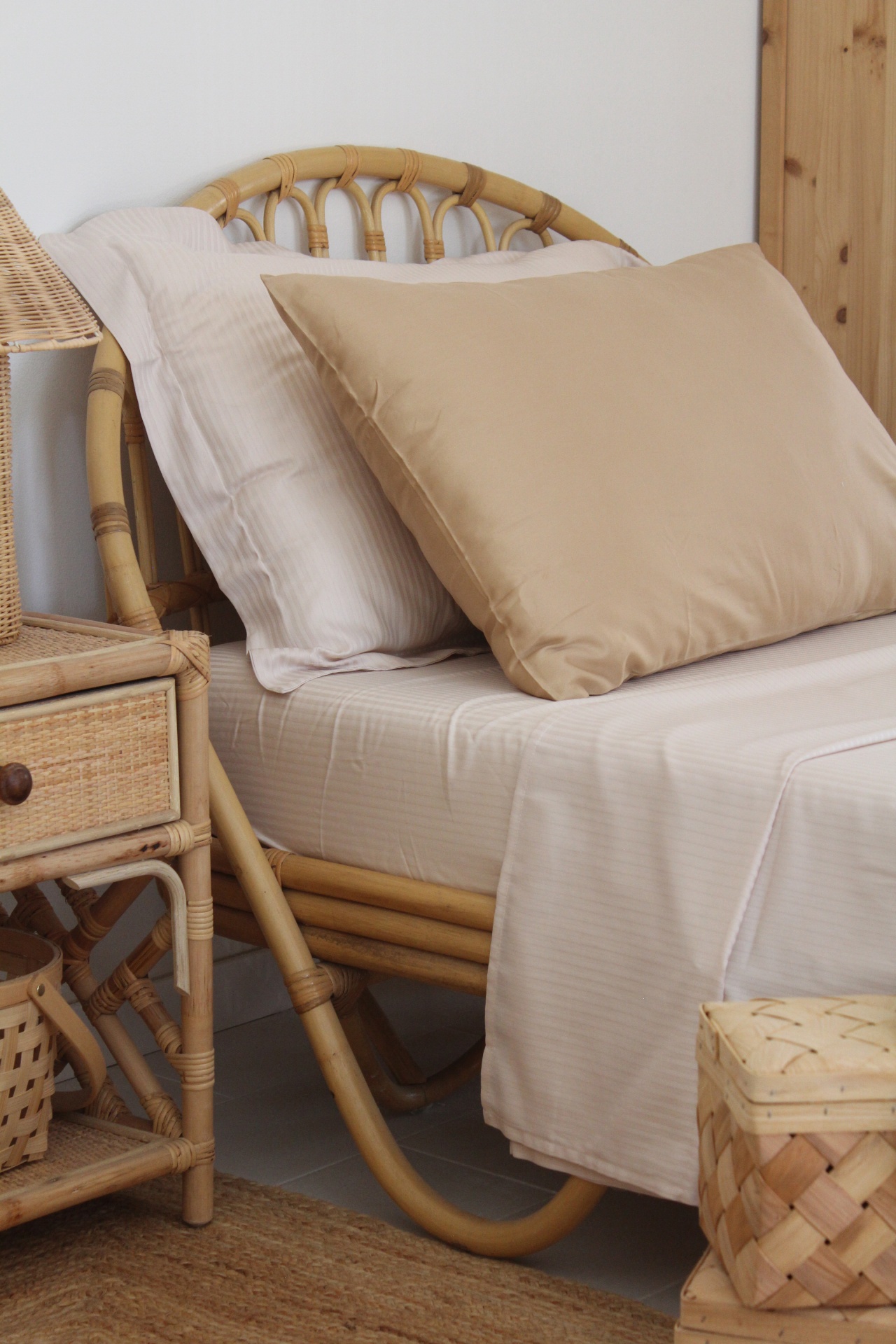 Cama com estrutura de vime e roupa de cama branca e almofada bege