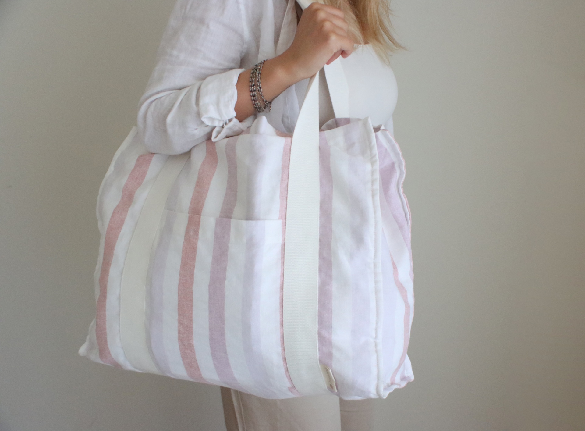 Mala de tecido às riscas em tons claros usada ao ombro