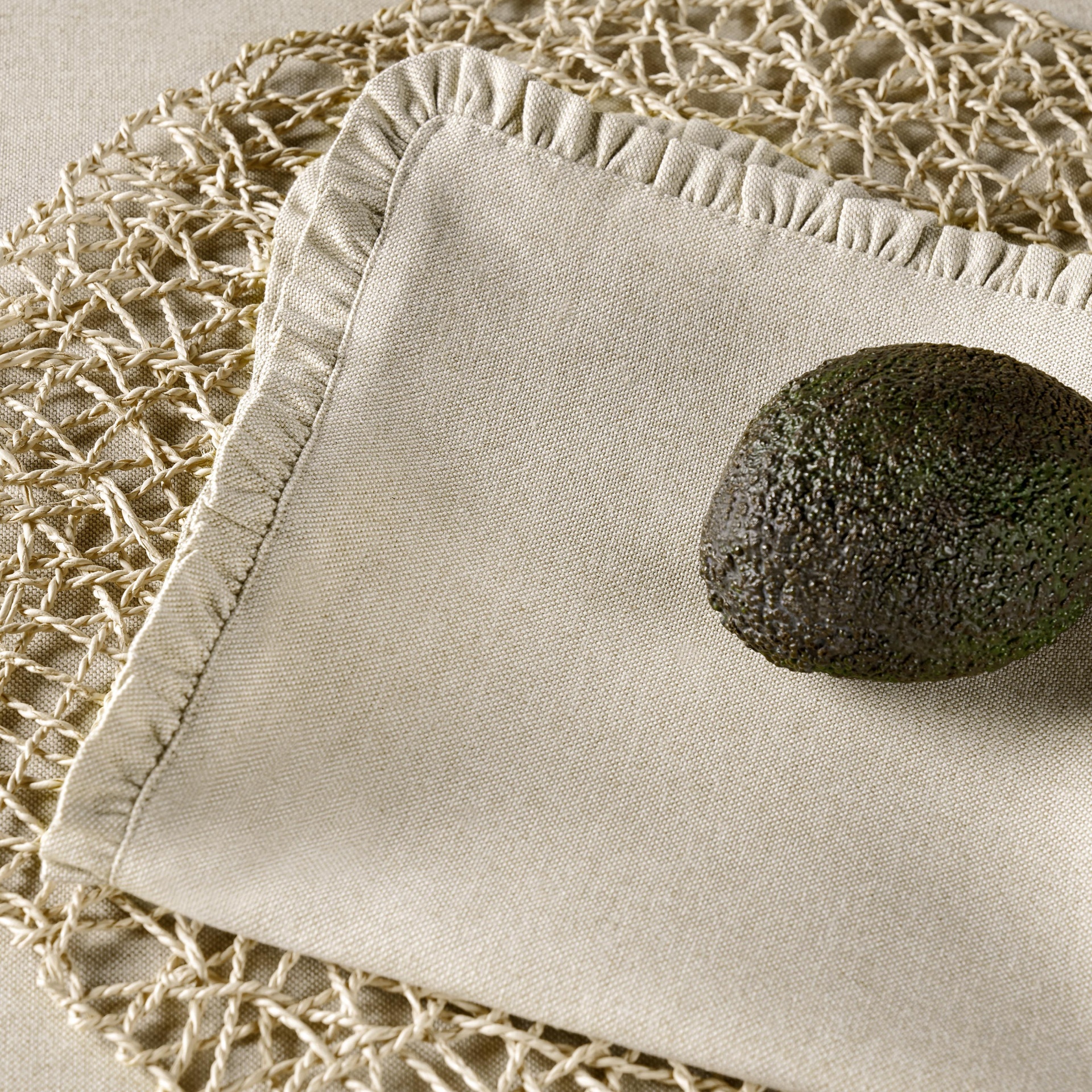 Abacate sobre guardanapo bege e base entrelaçada clara