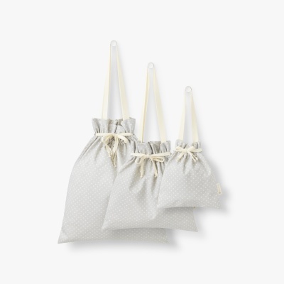 Conjunto de três sacos de tecido cinza claro com padrões de pontos brancos e cordões creme
