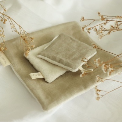 Três panos de tecido neutros com raminhos secos sobre tecido branco.