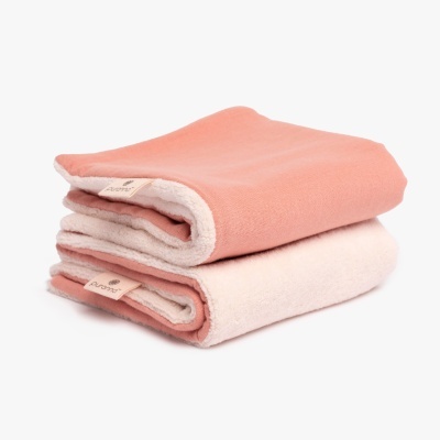 Duas mantas dobradas cor de salmão e rosa pálido com etiquetas de tecido