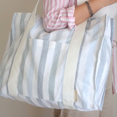 Mala de tecido riscada em azul claro e branco com alças brancas