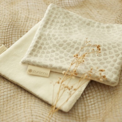 Duas bolsas pequenas em tecido creme e bege com padrão de corações, sobre tecido bege quadriculado com flores secas