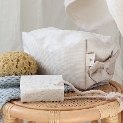 Produtos de banho dispostos sobre um banco de rattan redondo.