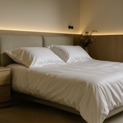 Cama de casal com roupa branca e estrutura estofada bege