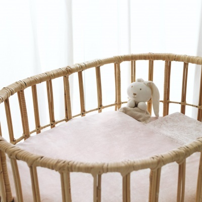 Berço de rattan natural com colchão rosa e peluche de coelho branco