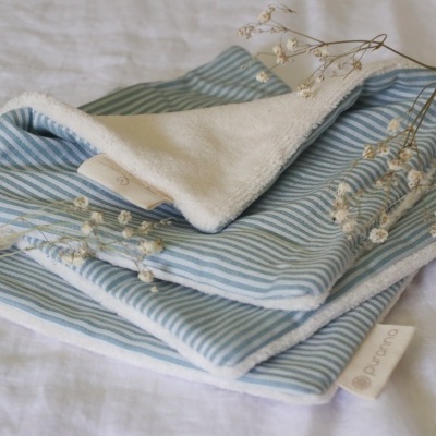 Toalha azul riscada com interior branco felpudo e raminhos secos