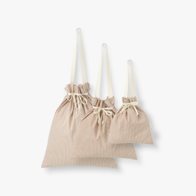 Três sacos de tecido bege com cordões e alças brancas pendurados