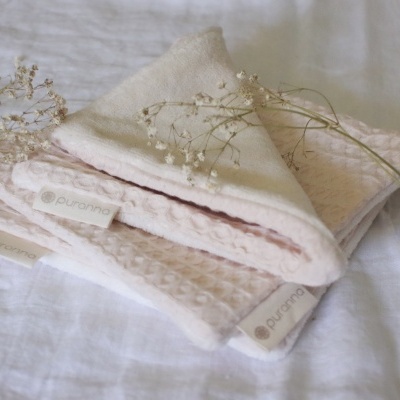 Toalhas cor de rosa claro com etiqueta Puranos e flores secas sobre tecido branco