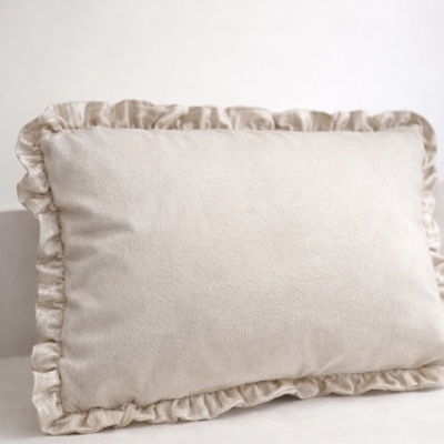 Almofada bege claro com borda franzida sobre superfície semelhante