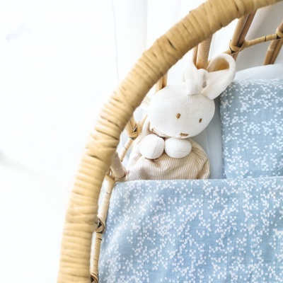 Boneco de peluche coelho numa cama com lençóis azuis e estrutura de bambu