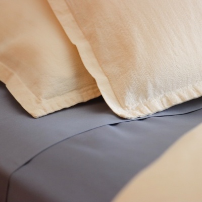 Travesseiros com fronhas amarelas claras sobre lençol cinza