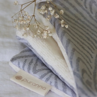 Pano cinzento com padrão e etiqueta puurranna com flores secas em cima