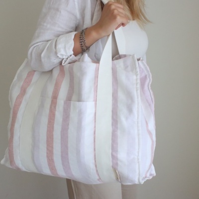 Mala de tecido às riscas em tons claros usada ao ombro