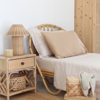 Quarto com cama e mesa de apoio em rattan, caixas de vime e tapete de fibras naturais