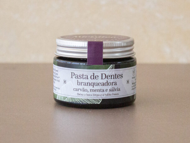 Pasta de Dentes Branqueadora Frasco de pasta de dentes branqueadora com carvão, menta e sálvia sobre superfície castanha