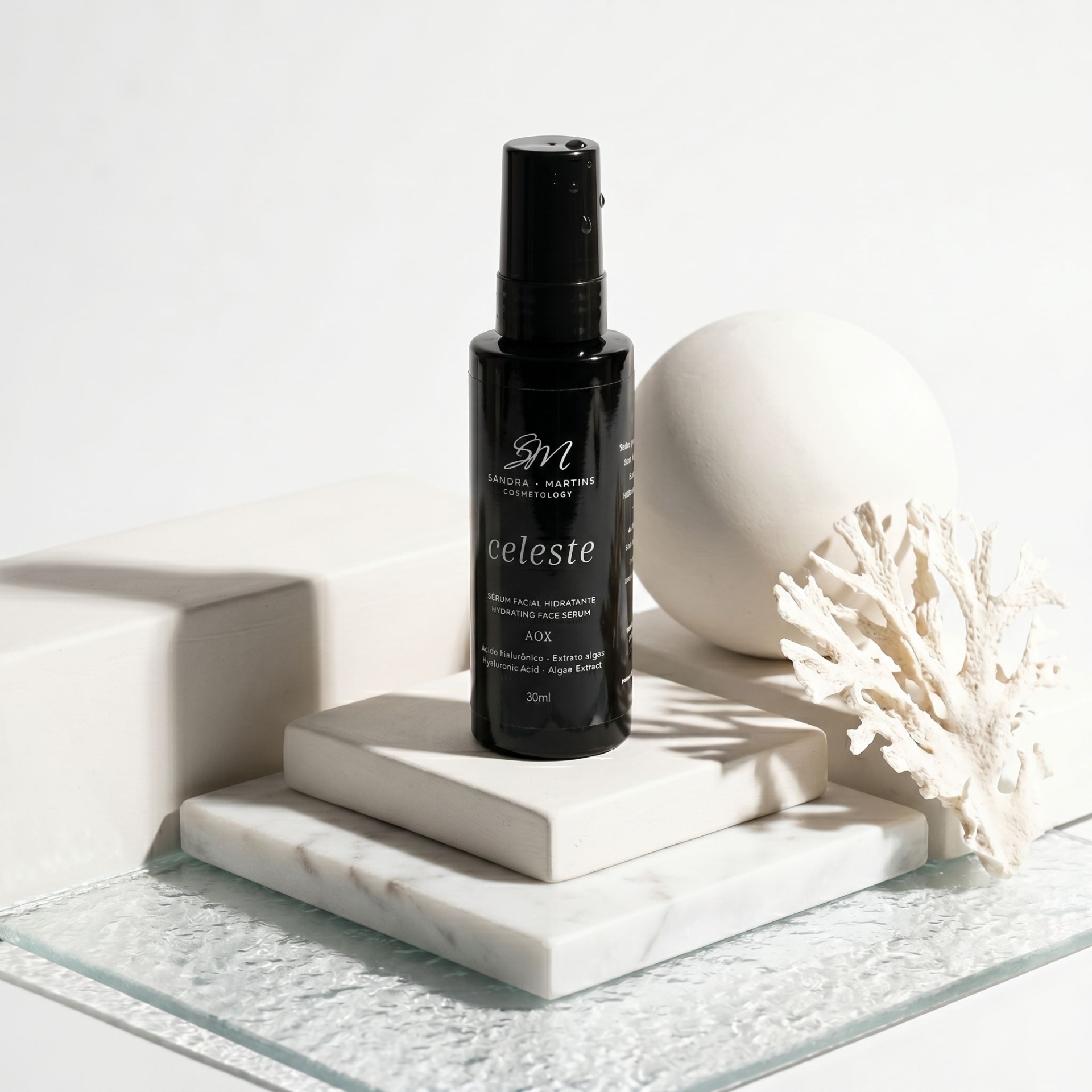 Sérum Facial Celeste Frasco preto de spray cosmético celeste sobre mármore branco com decoração branca