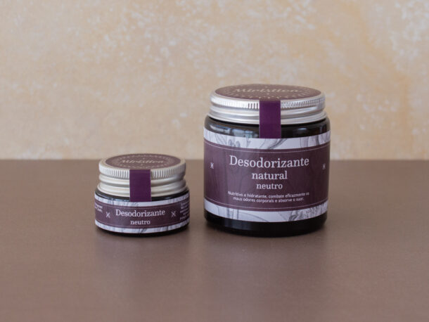 Desodorizante Neutro Dois frascos de desodorante natural neutro com rótulos roxos em superfície castanha