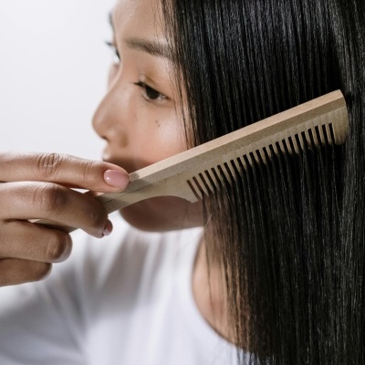 Mulher penteando cabelo com pente de madeira