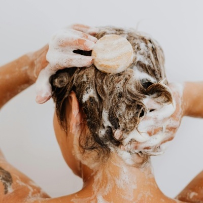 Pessoa a lavar o cabelo com sabão sólido e espuma branca