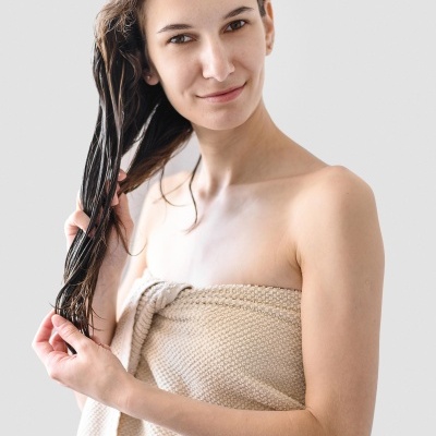 Mulher com cabelo molhado e toalha bege