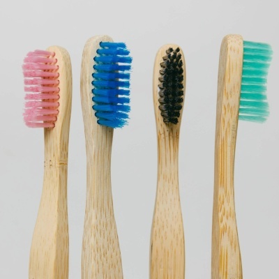 Quatro escovas de dentes com cabos de madeira e cerdas coloridas