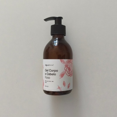 Frasco castanho com doseador preto e etiqueta branca com flores rosa e texto de gel corporal e capilar