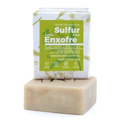 Sabão de enxofre com embalagem verde e branca colocado sobre sabão bege sem embalagem