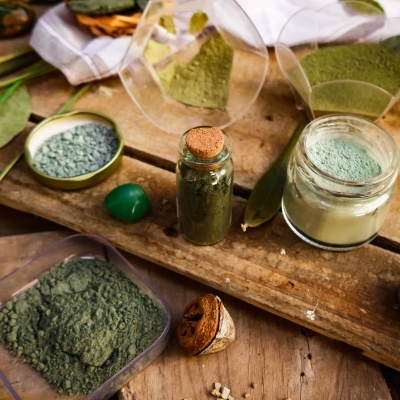 Frascos com pó verde em diferentes tons numa superfície de madeira