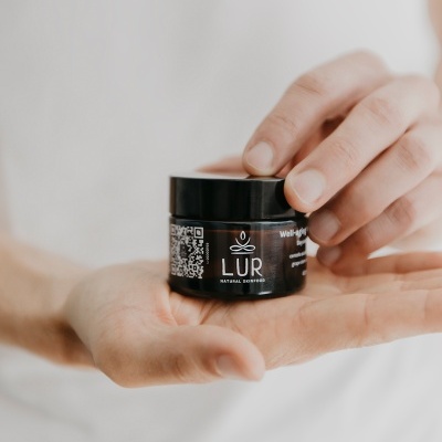 Frasco pequeno de creme LUR Natural Skinfood na mão