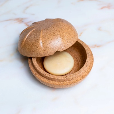 Caixa redonda castanha com tampa texturada semelhante a pão com botão interior redondo creme