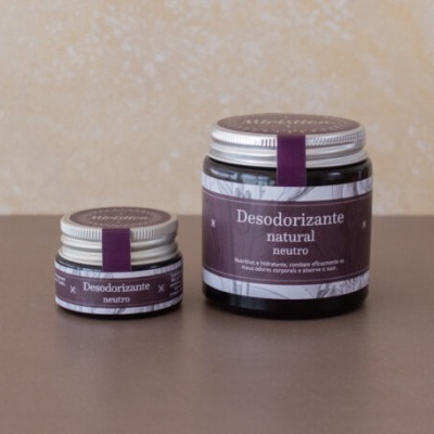 Dois frascos de desodorante natural neutro com rótulos roxos em superfície castanha