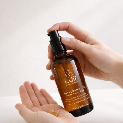 Frasco de Vegan Cleansing Oil LUR com embalagem castanha e tampa preta em mãos femininas