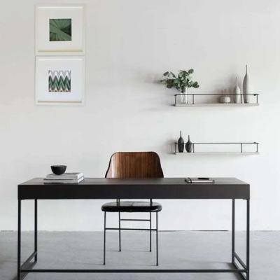 Secretária preta com cadeira em madeira e metal, prateleiras de parede com decoração e quadros geométricos