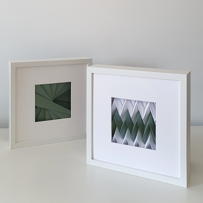 Dois quadros brancos com padrões geométricos de papel verde e branco em relevo