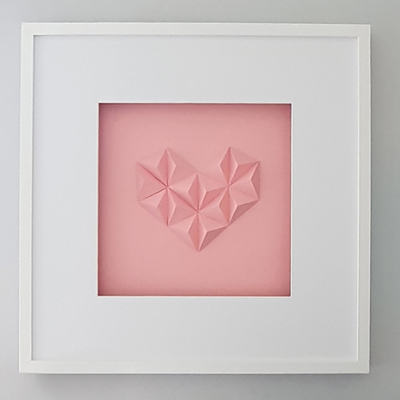 Quadro decorativo com coração tridimensional rosa emoldurado a branco pendurado na parede