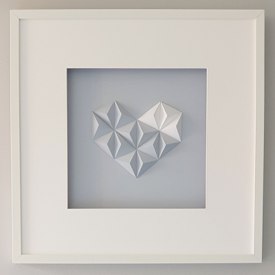 Quadro branco com escultura geométrica em forma de coração em fundo cinzento claro