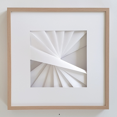 Quadro com padrão geométrico em relevo branco dentro de moldura de madeira clara