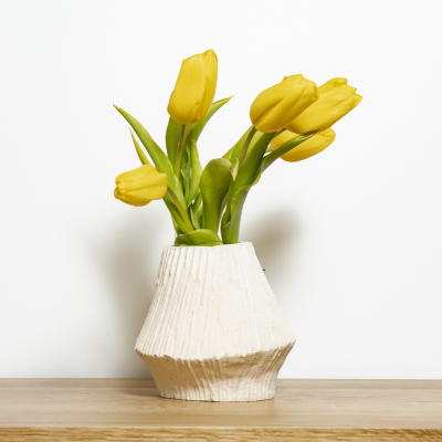 Vaso cerâmico branco texturizado com tulipas amarelas em superfície de madeira