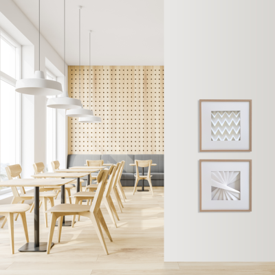 Sala de refeições moderna com cadeiras e mesas de madeira clara e arte geométrica em molduras na parede branca