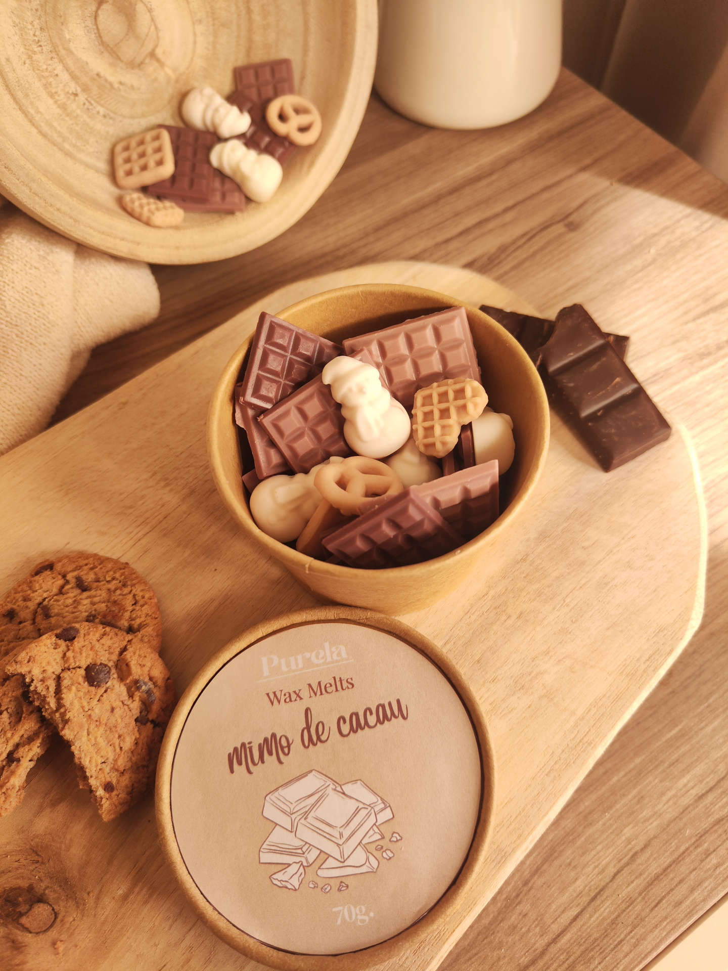 Wax Melt Mimo de Cacau Copo com Wax Melts em forma de chocolate e rótulo Purela Wax Melts mimo de cacau 70g sobre tabuleiro com biscoitos