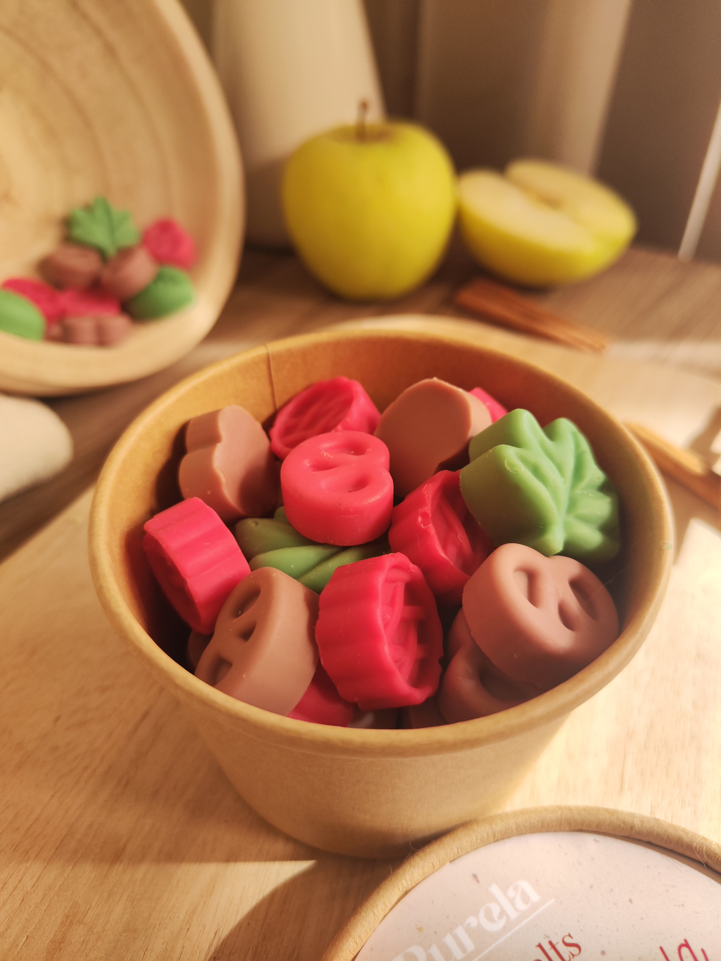 Wax Melt Maçã e Canela Pastilhas coloridas em caixa de cartão com maçã amarela e canela ao fundo